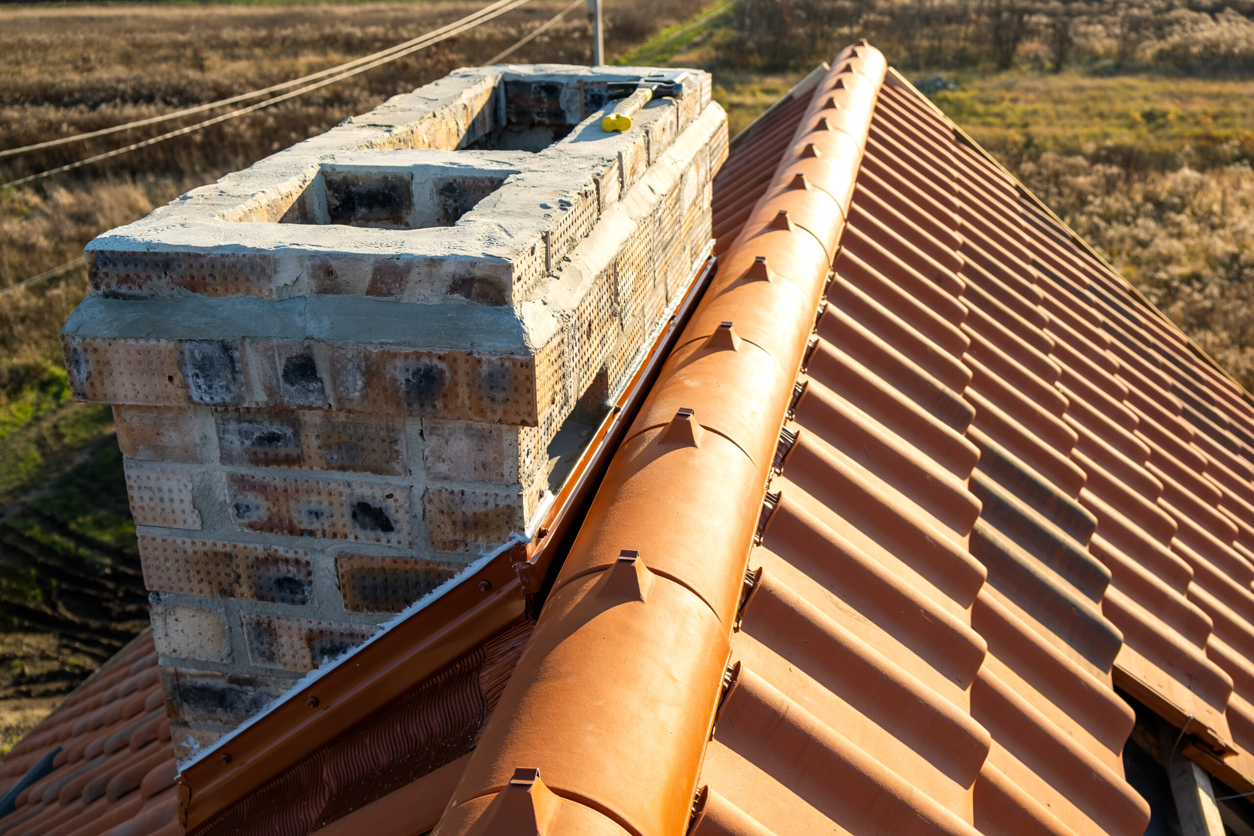 Closeup of yellow ceramic roofing ridge tiles on top of residential building roof under construction.