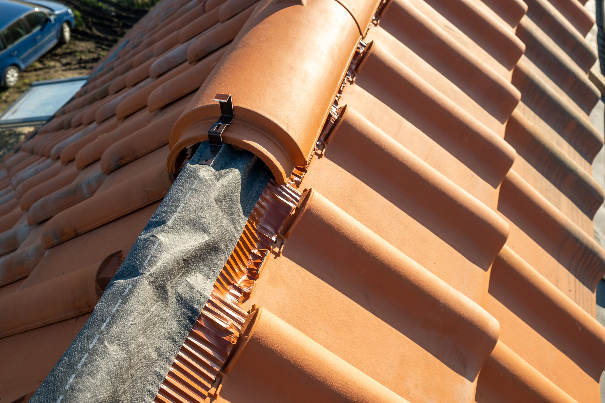 Closeup of yellow ceramic roofing ridge tiles on top of residential building roof under construction.