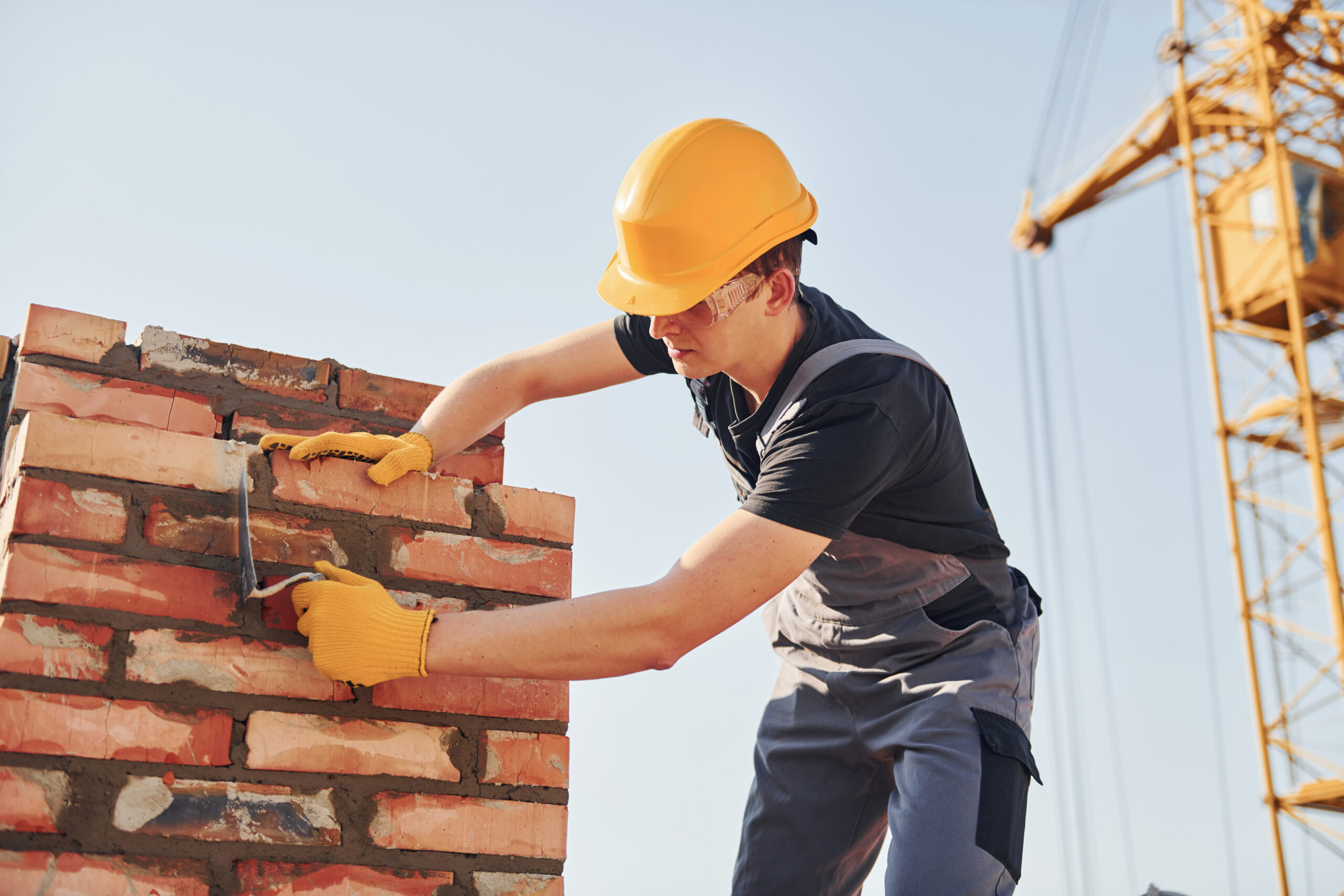 Installing brick wall. Construction worker in uniform and safety equipment have job on building