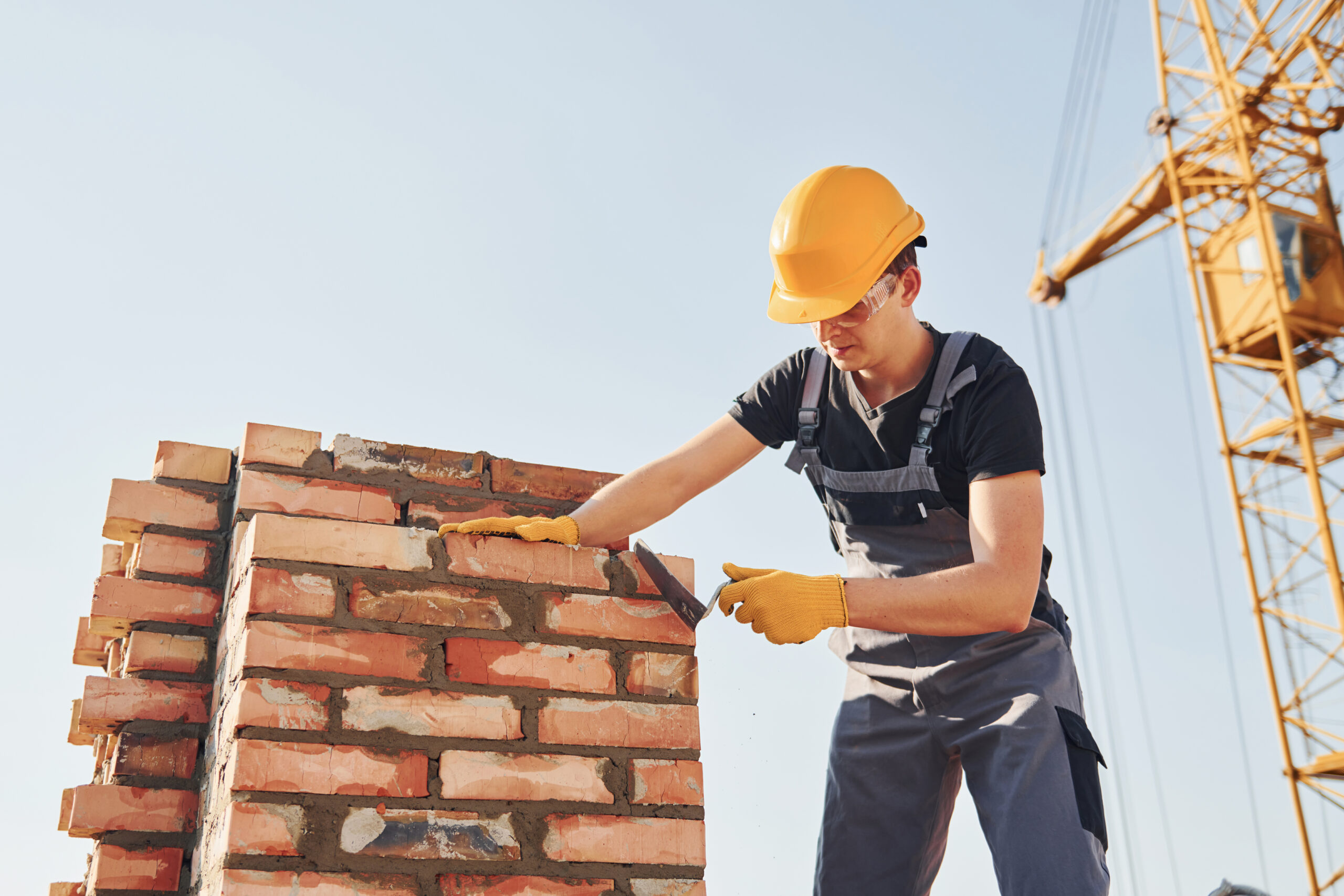 Installing brick wall. Construction worker in uniform and safety equipment have job on building