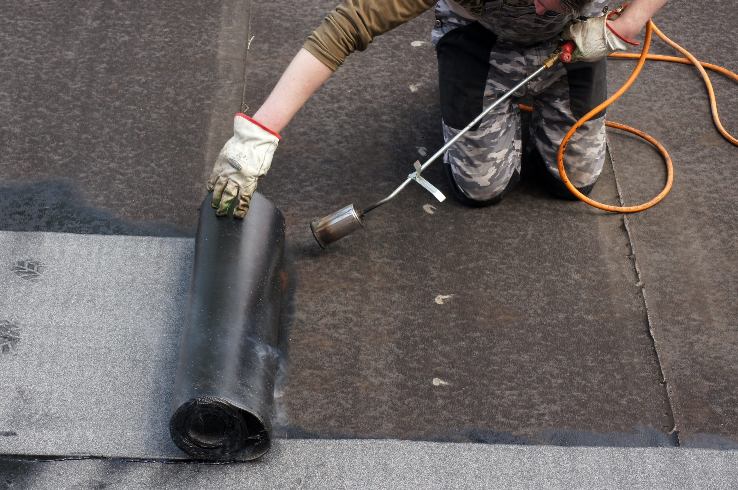 Worker doing roofers welding line with a gas torch